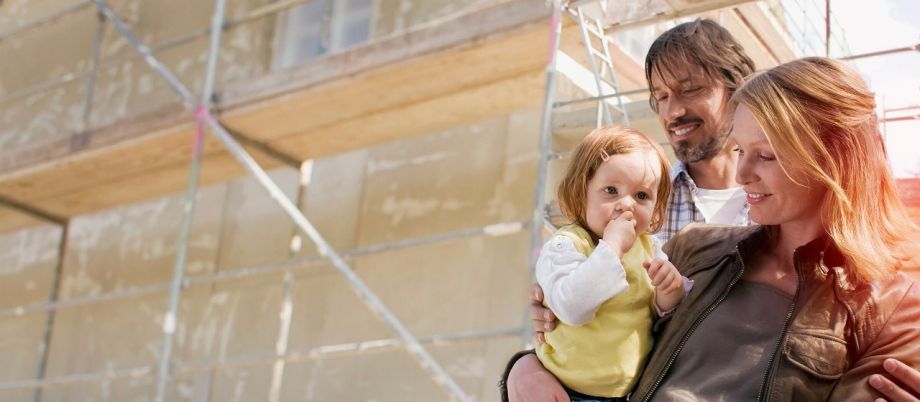 Paar mit Kind auf dem Arm auf einer Baustelle